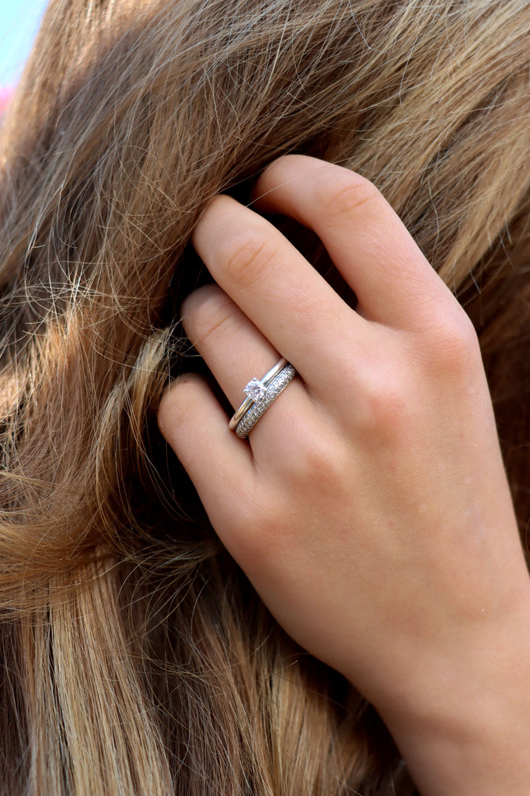 Tjej som bär ett set med vigselring och förlovningsring i silver med diamanter.