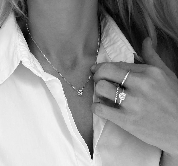Tjej som bär ett halsband med liten silverknut. 